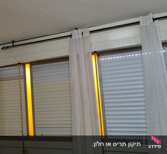 תריסים לבנים עם פסי אור צהובים ביניהם
